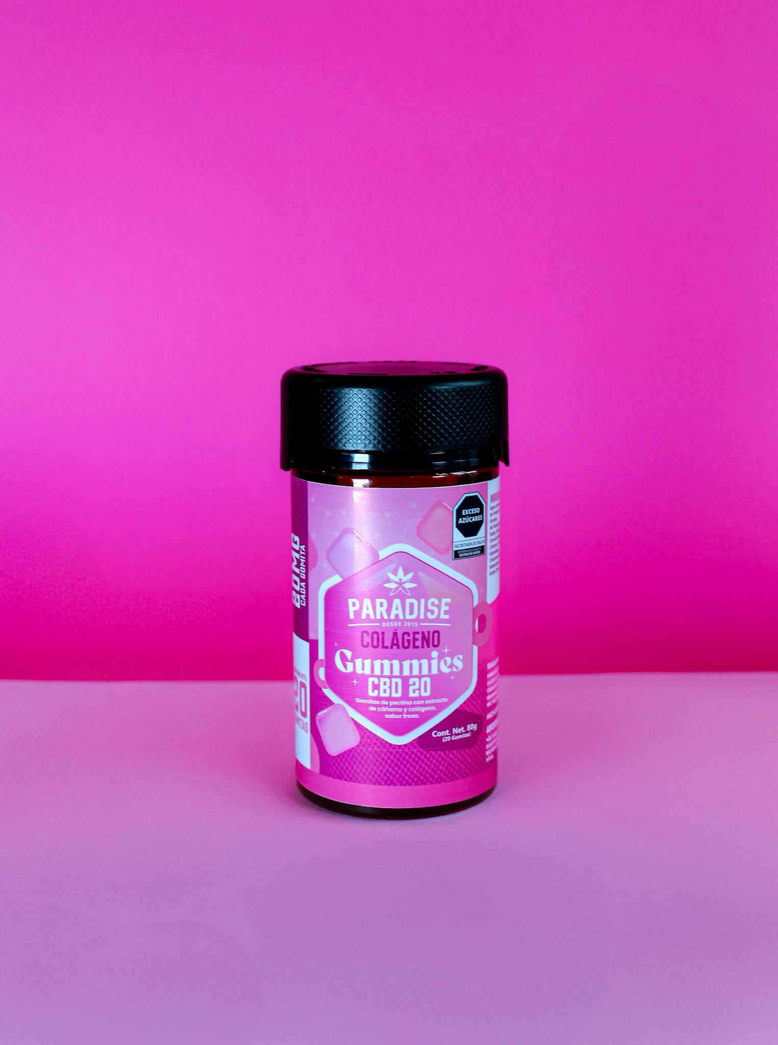 Vibrant pink bottle of collagen CBD gummies on a matching pink background.