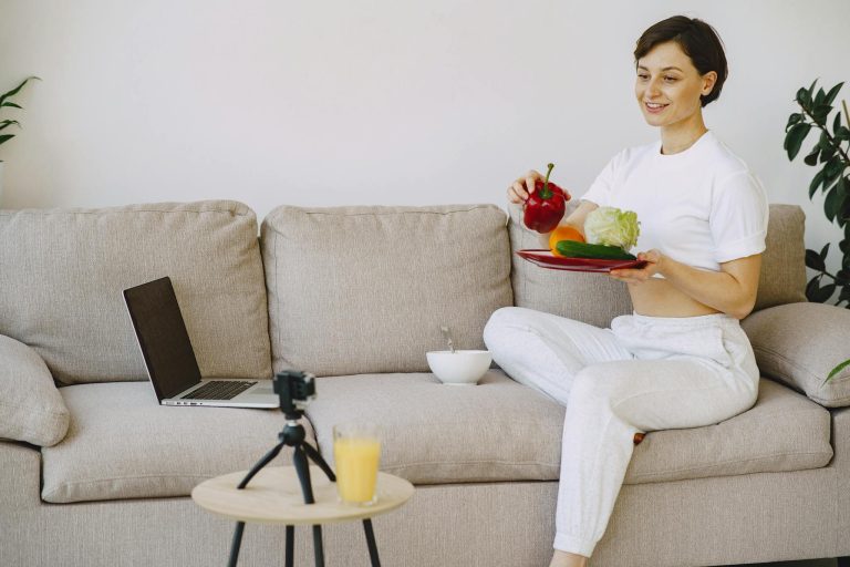 Woman vlogger prepares fresh vegetables while filming with a digital camera indoors.